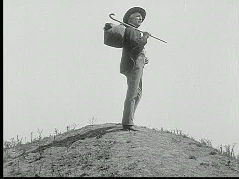 wide-shot-old-man-carrying-knapsack-and-cane-stands-atop-hill-during-video-id1232-140s640x6402466d.jpg