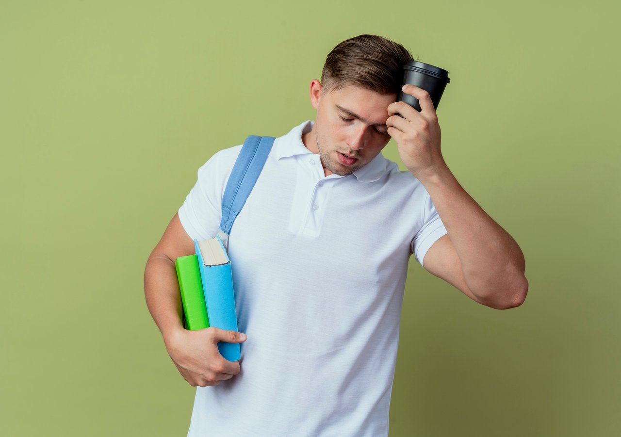 with-closed-eyes-tired-young-handsome-male-student-wearing-back-bag-holding-books-putting-cup-coffee-forehead-isolated-olive-green.jpg