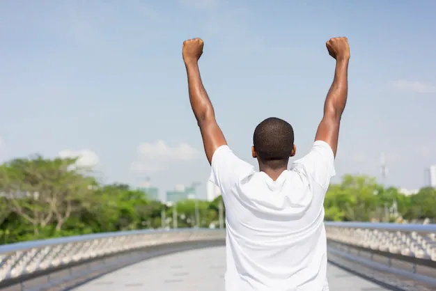 back-black-man-enjoying-city-view-raising-both-hands_1262-12606.webp