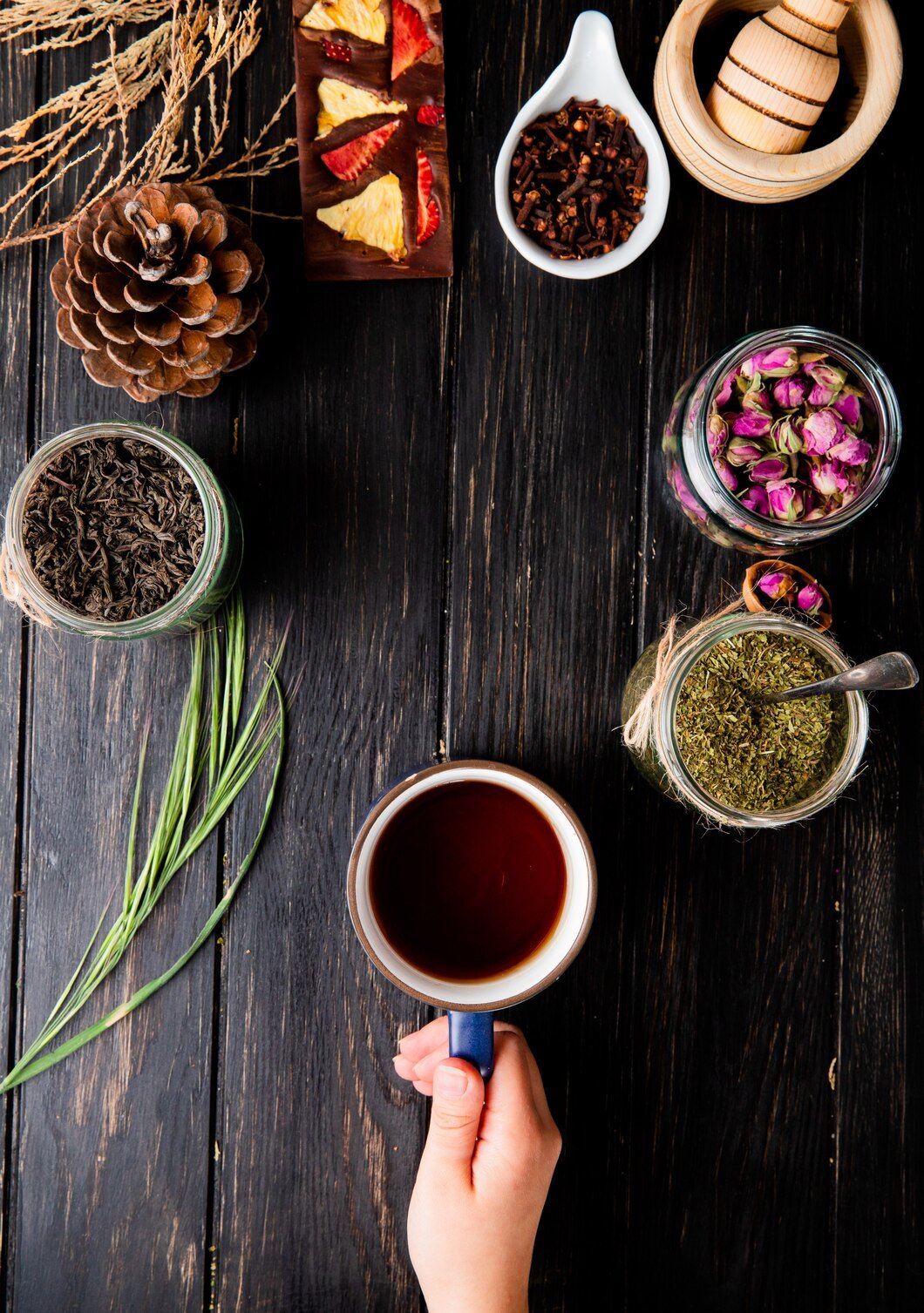 top-view-hand-holding-cup-tea-various-spices-herbs-black-wood-with-copy-space_141793-7440.jpg