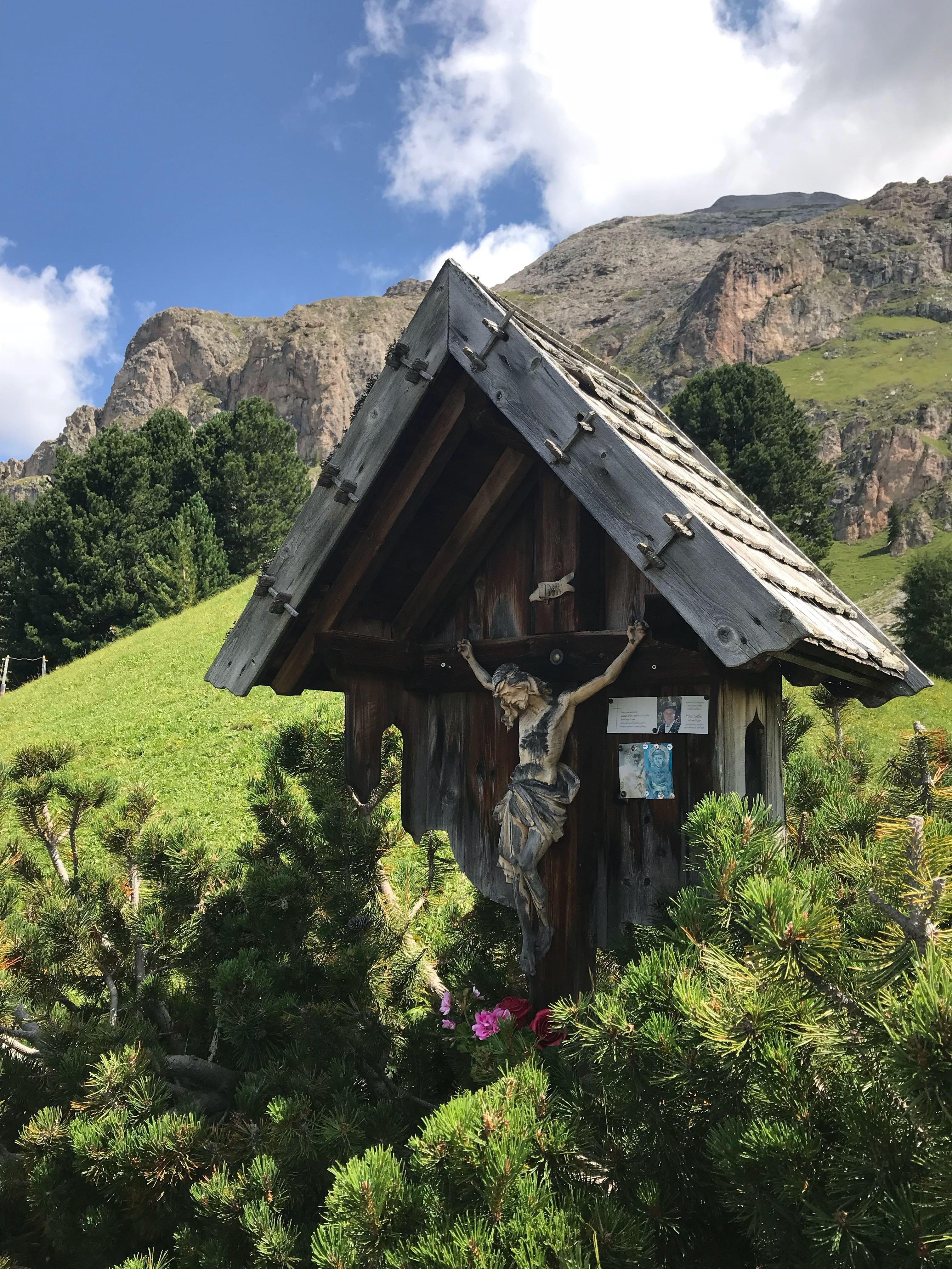 Christ's wood sculpture under Sassopiatto mountain