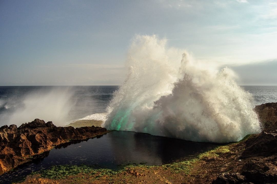 Waves are driving up against a sand cliff...