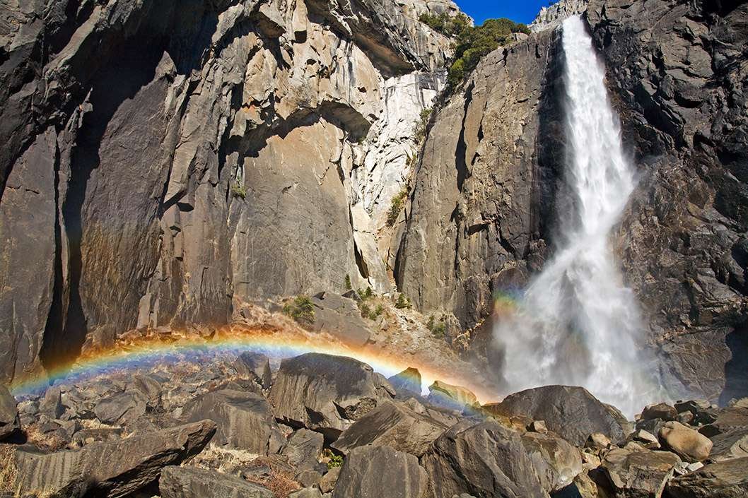 A rainbow forms at the base of Yosemite Falls. 