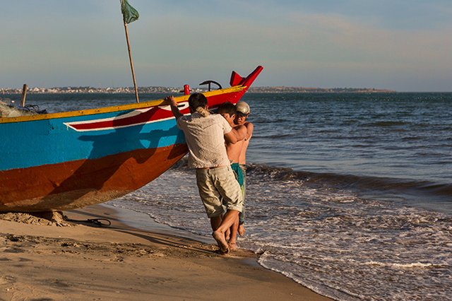 Putting the fishing boat into the water at the Beach in Hàm Tiến