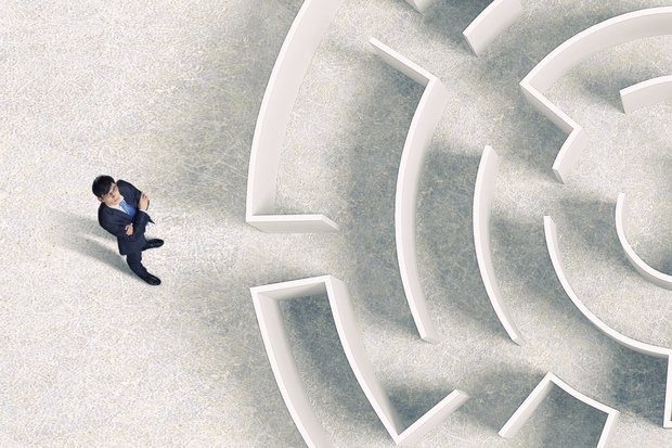 Picture of a man looking upon a maze entrance, thinking.