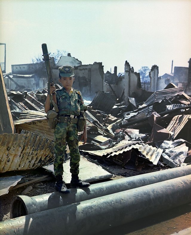 Tan Son Nhut, Vietnam, 1968. A twelve year old Vietnamese ARVN Airborne trooper who had been "adopted" by the Airborne Division, holding a M-79 grenade launcher. The picture was taken during a sweep of an Airborne Task Force Unit through the devastated area surrounding the French National Cemetery on Plantation Road after a day long battle there.