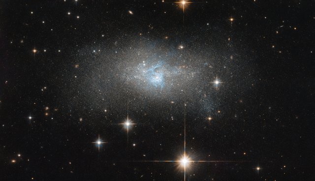 A ripple of bright blue gas threads through this galaxy like a misshapen lake system.
