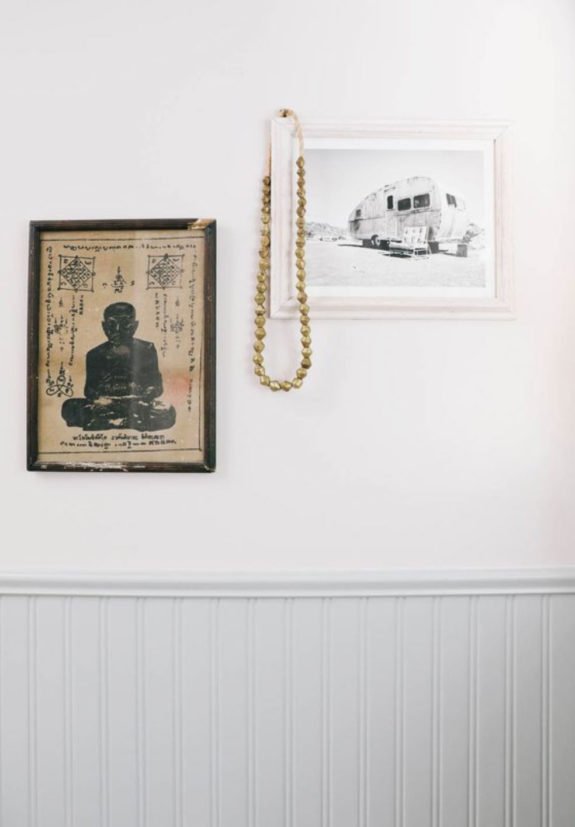 framed vintage prints hung with wooden beads on white wall. / sfgirlbybay