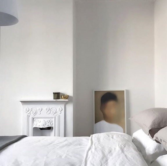 white bedroom with unique art and small fireplace. / sfgirlbybay