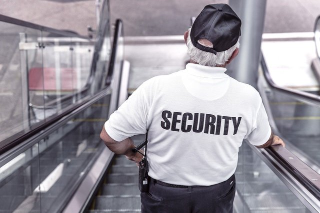 elderly security guard going down escalator
