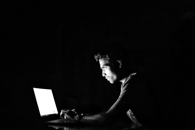 man in dark room using computer