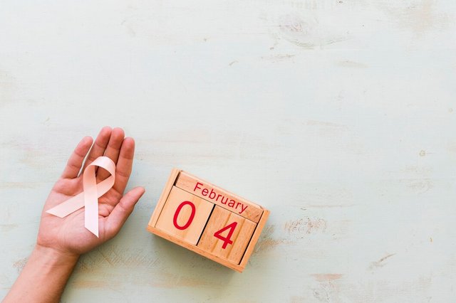 hand-holding-pink-awareness-ribbon-4th-february-wooden-box-backdrop_23-2147863646.jpg