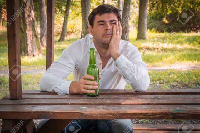 74517590-lonely-drunk-man-sitting-on-a-bench-and-holding-a-beer-bottle-in-park.jpg