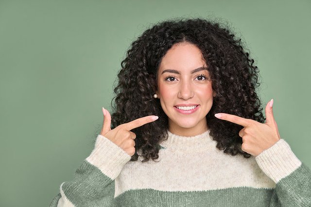 happy-young-woman-pointing-at-white-healthy-teeth-2023-03-27-20-07-26-utc.jpg