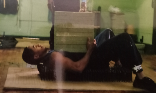 Michaelson Williams on a bed of nails with 10 concrete blocks on his body.png