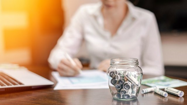 jar-with-rolled-banknotes-table-laptop-papers-woman-background_1268-17481.jpg