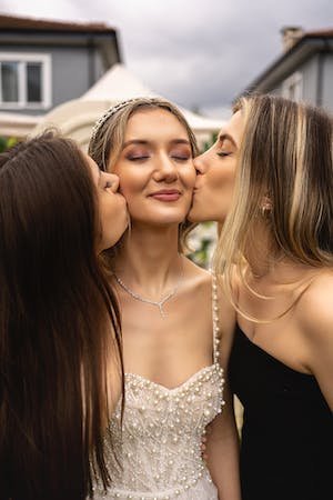 free-photo-of-two-young-women-cheek-kissing-a-bride-at-wedding.jpeg