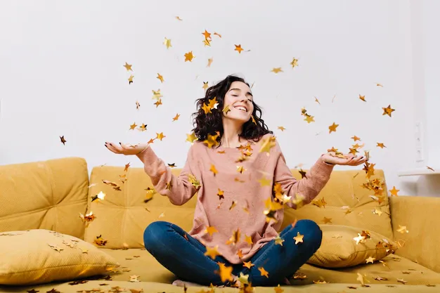 expressing-true-positive-emotions-young-joyful-woman-with-cut-curly-hair-having-fun-falling-tinsels-couch-modern-apartment-home-cosines-joy-smiling_197531-2232.webp