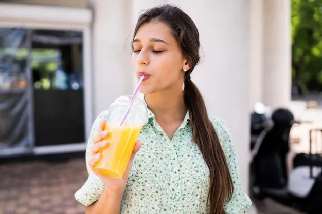 young-woman-smiling-drinking-cocktail-with-ice-plastic-cup-with-straw-city-street_1153-5895.webp