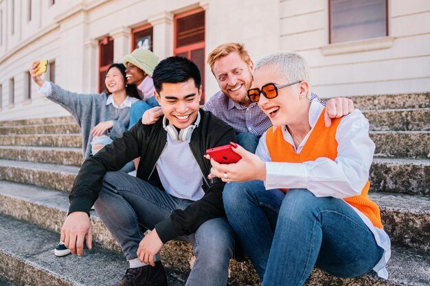 group-young-people-sitting-outdoor-watching-socialmedia-smartphone-happy-multiethnic-h_639864-2.jpg