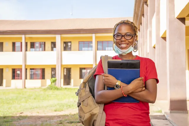 young-african-female-student-with-facemask-holding-her-textbooks-campus-area_181624-41232.webp