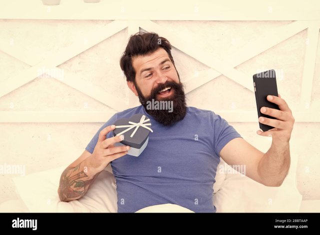 modern-life-is-impossible-without-communication-modern-hipster-with-gift-box-and-smartphone-bearded-man-make-video-call-with-modern-phone-modern-technology-change-way-we-celebrate-valentines-day-2BBTAAP.jpg