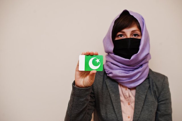 portrait-young-muslim-woman-wearing-formal-wear-protect-face-mask-hijab-head-scarf-hold-pakistan-flag-card-against-isolated-background-coronavirus-country-concept.jpg