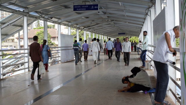 videoblocks-rush-hour-people-on-train-station-bridge-poor-beggar-looks-for-lice-mumbai_beimysnag_thumbnail-full01.png