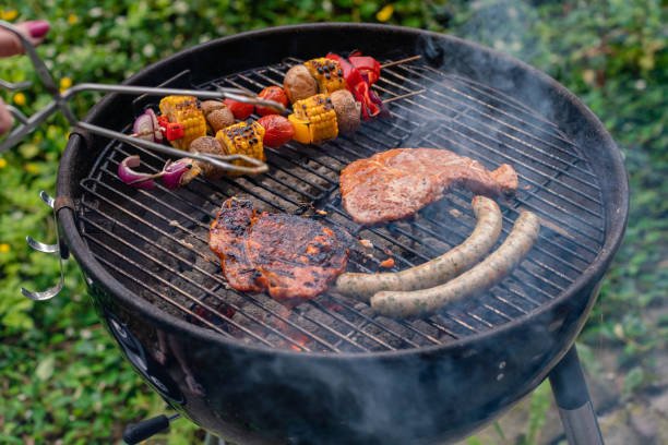 smoking-charcoal-grill-with-barbecue-tongs-grill-grate-with-steaks-sausages-and-vegetable.jpg