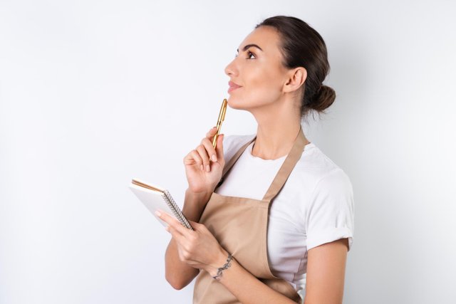 young-housewife-apron-white-background-with-notebook-her-hands-chooses-recipes-dinner-thinks-how-please-her-husband-comes-up-with-ideas-dishes.jpg