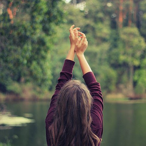back view of woman with arms raised in a forest setting.jpg