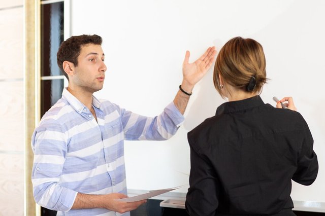 front-view-young-attractive-businesswoman-black-shirt-along-with-young-man-discussing-graphics-desk-while-young-lady-presents-her-work-reading-document-job-building-presentation_140725-16125.jpg