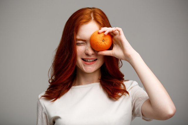 beautiful-ginger-girl-holding-orange-gray-wall_176420-446.jpg