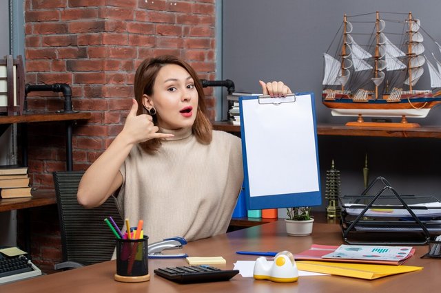 front-view-pretty-woman-holding-clipboard-making-call-me-sign-office_140725-109229.jpg