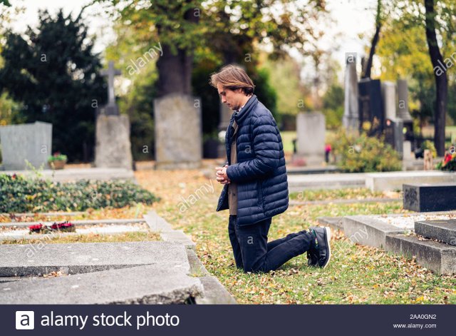 duelo-joven-arrodillado-delante-de-una-tumba-en-un-cementerio-durante-un-triste-dia-de-otono-2aa0gn2.jpg