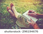 stock-photo-female-hands-with-pen-writing-on-notebook-on-grass-outside-296194676.jpg