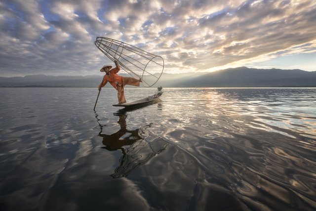 Burmese Fisherman on the Boat with Traditional Conical Net in the Morning, Lake Inle, Myanmar.jpg