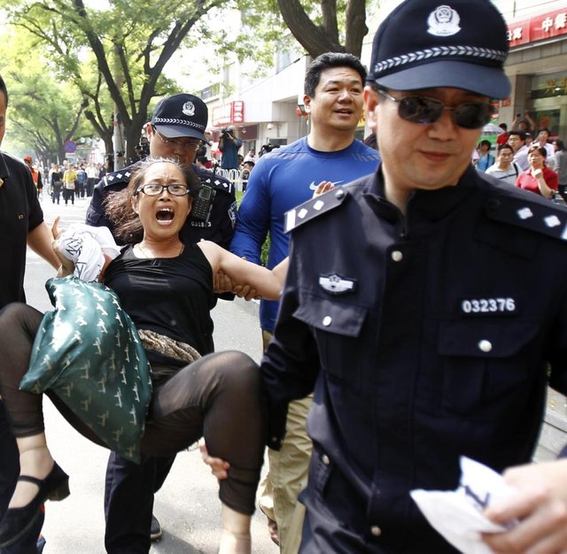 Police-carry-away-a-woman-who-started-a-protest-for-personal-economic-reasons-in.jpg