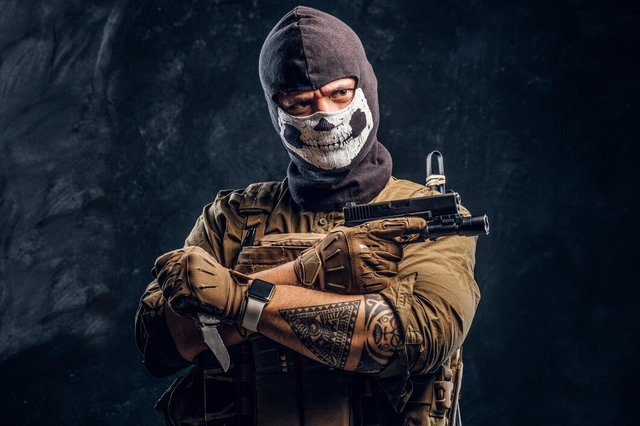 terrorist-military-uniform-skull-balaclava-holding-pistol-knife-looks-camera-with-menacing-look-studio-photo-against-dark-textured-wall_613910-20880.jpg