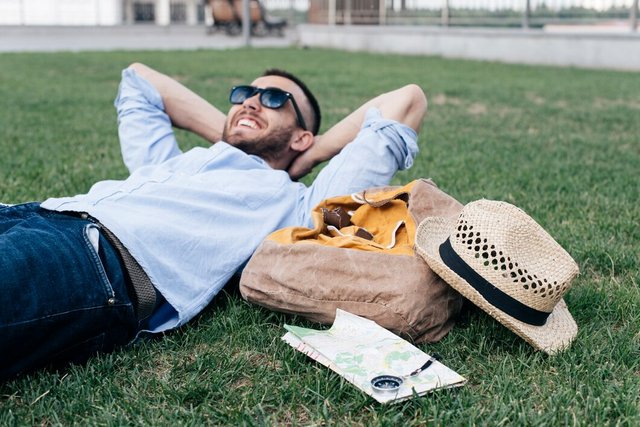 relaxed-smiling-man-lying-grass-with-travelling-accessories_23-2148202994.jpg