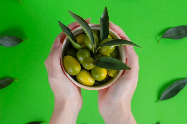 female-hands-holding-bowl-full-fresh-green-cumquats-with-leaves_114579-42616.jpg