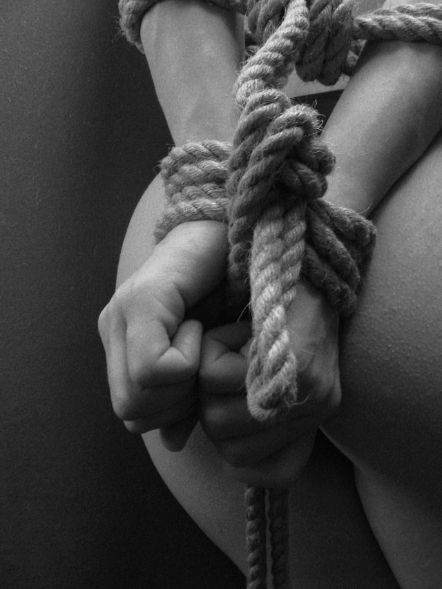 Mujer atada de manos con cuerdas en la cama.jpg