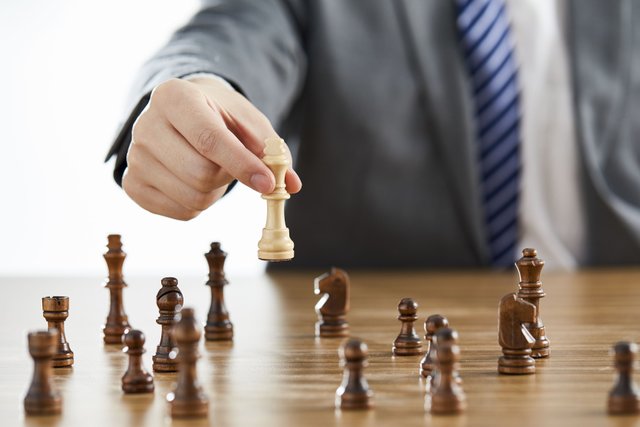 businessman-suit-using-his-white-king-chess-piece-among-dark-chess-pieces-table (1).jpg