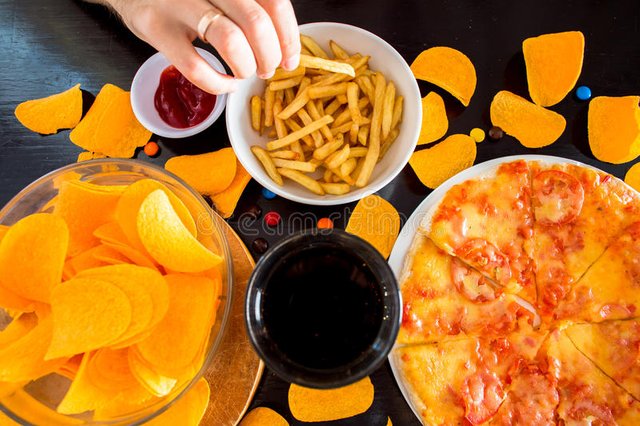 fast-food-unhealthy-eating-concept-close-up-pizza-fre-french-fries-potato-chips-candies-wooden-table-top-view-67556100.jpg