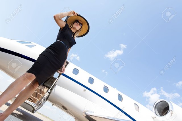 25762145-ngulo-de-visión-baja-de-una-mujer-en-el-elegante-vestido-de-pie-en-frente-de-jet-privado-contra-el-ciel.jpg