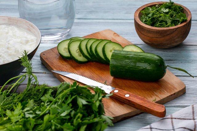 side-view-sliced-cucumbers-board-with-knife-greens-gray-surface_141793-18102.jpg