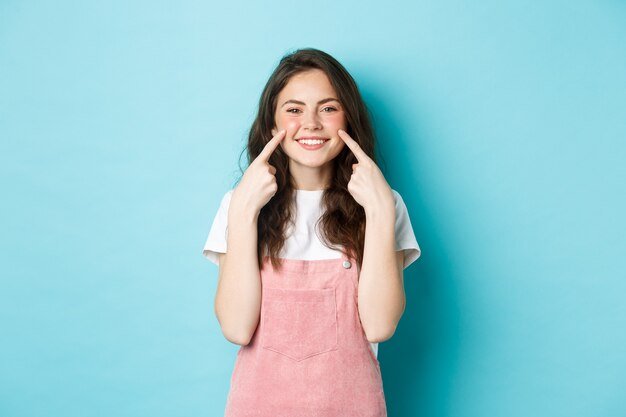 portrait-beautiful-summer-girl-poking-cheeks-showing-dimples-smiling-white-teeth-standing-blue-background_1258-69939.jpg