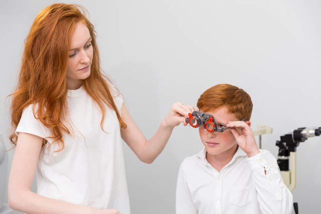 young-female-optician-wearing-optometrist-trial-frame-cute-boy-checking-his-eyes.jpg