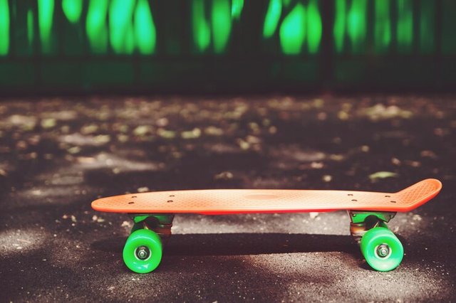 close-up-orange-penny-skateboard-asphalt-green-wall_158538-13802.jpg