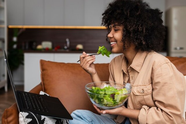 afro-american-woman-eating-salad-looking-laptop_23-2148363617.jpg